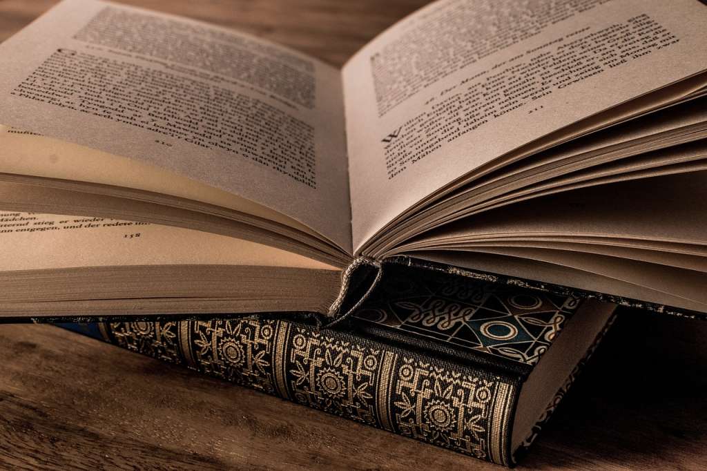 A book spread out on top of another book on a wooden table