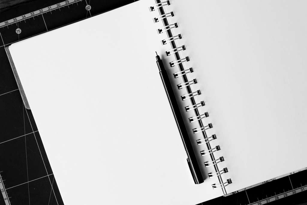 A notebook, a pen and some rulers on a black background