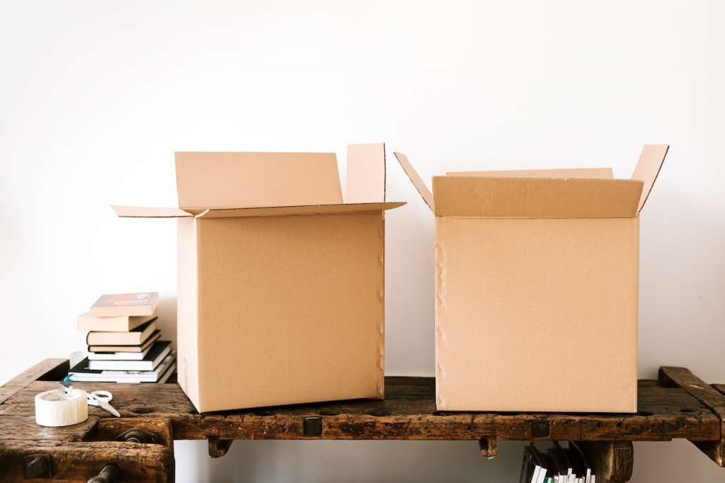 Two unclosed cardboard boxes lie on a wooden table