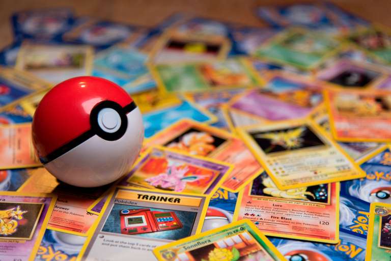 A red and white Pokémon ball on a stack of Pokémon cards